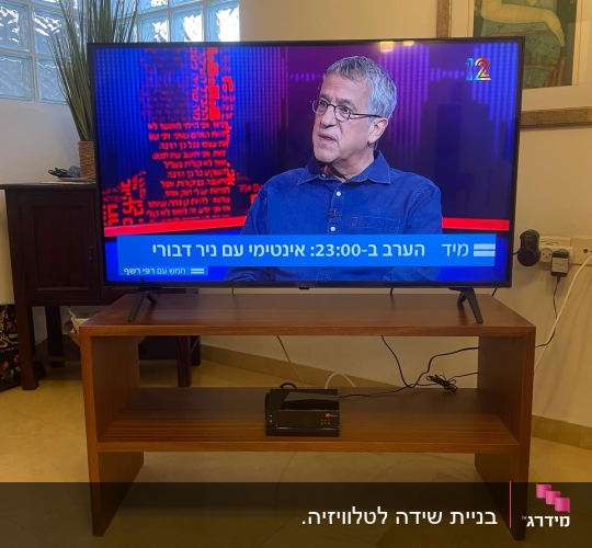 טלוויזיה על שולחן עץ עם מכשיר אלקטרוני